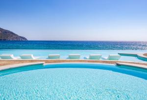 a swimming pool with chairs and the ocean in the background at Konstantinos Palace in Karpathos