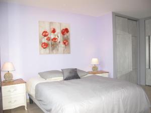 1 dormitorio con 1 cama blanca con flores rojas en la pared en Holiday Home Les Piboules - LLI150, en Callian