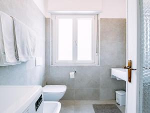 a white bathroom with a toilet and a window at Holiday Home Villetta ai Pini-2 by Interhome in Calceranica al Lago +26 photos