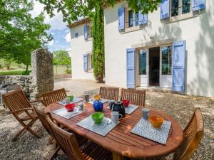 a wooden table with chairs in front of a house at Holiday Home Les Cotes by Interhome in Saint-Martin-de-Castillon