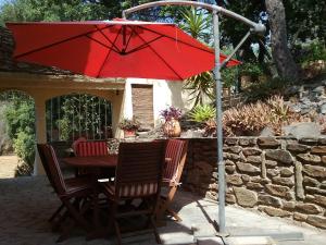 グリモーにあるGrimaud Golfe de St Tropez Var Côte d'Azurのパティオ(赤い傘付きのテーブルと椅子付)