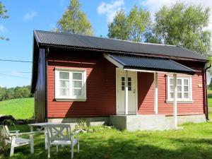 una pequeña casa roja con una mesa delante en Chalet Flatebygd - SOO355 by Interhome, en Evje