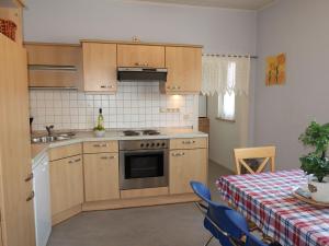 a kitchen with wooden cabinets and a table with a table cloth at Apartment Petra by Interhome in Nentershausen