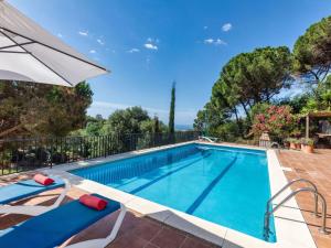 a swimming pool with two chairs and an umbrella at Holiday Home Balmain by Interhome in Lloret de Mar