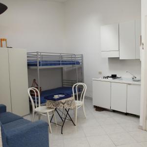 salon ze stołem, krzesłami i łóżkiem piętrowym w obiekcie Villini Sulla Spiaggia w mieście Capoliveri