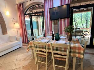 Un comedor con una mesa con sillas y un televisor. en Apartment Istrice-10 by Interhome, en Riparbella