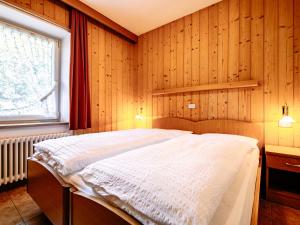 a bedroom with a bed in a wooden wall at Apartment Cincelli by Interhome in Pozza di Fassa