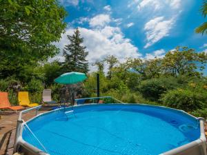 a swimming pool with an umbrella and chairs and a table at Holiday Home Villa Hofbauer by Interhome in Dobreć