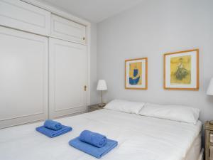 biała sypialnia z 2 niebieskimi ręcznikami na łóżku w obiekcie Apartment Calahonda Royale by Interhome w mieście Sitio de Calahonda