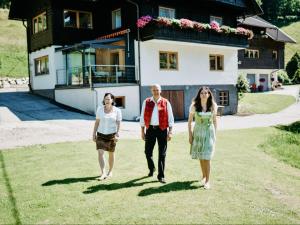 three people walking in front of a house at Apartment Enzian by Interhome in Arriach