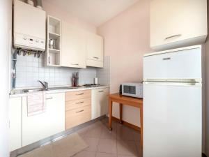 cocina con armarios blancos y nevera blanca en Apartment Squisleep-2 by Interhome en San Daniele del Friuli