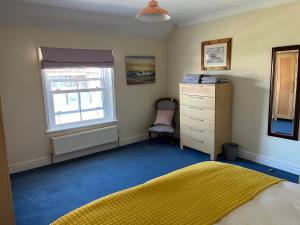 a bedroom with a bed and a dresser and a window at Stunning 1-Bed Apartment in Sheringham in Sheringham