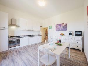biała kuchnia z białym stołem i krzesłami w obiekcie Holiday Home Elena by Interhome w mieście Altopascio