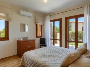 a bedroom with a bed and a desk and windows at Apartment Apartment Aphrodite Hills Golf by Interhome in Kouklia