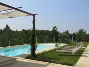 a swimming pool with two benches and an umbrella at Holiday Home Tenuta Margherita by Interhome in Portacomaro