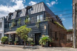 a black brick building with plants on it at Communal Hotel Plekhanovi in Tbilisi City
