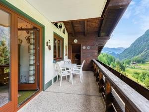 a balcony of a house with a table and chairs at Apartment Glockner-2 by Interhome in Heiligenblut