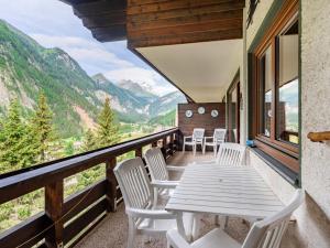 een tafel en stoelen op een balkon met uitzicht op de bergen bij Apartment Glockner-2 by Interhome in Heiligenblut