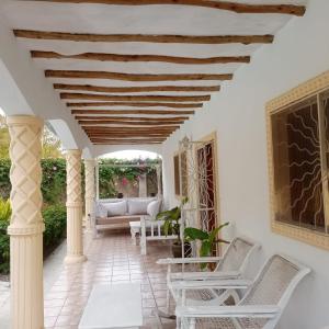 a porch with white chairs and a couch at 2 Bedroom Mangrove Cottage with Private Pool in Watamu