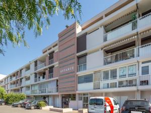 an apartment building with cars parked in front of it at Apartment Le Carthage by Interhome in Carqueiranne