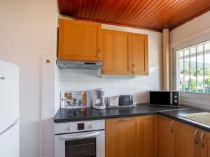 a kitchen with wooden cabinets and a stove top oven at Apartment Le Carthage by Interhome in Carqueiranne