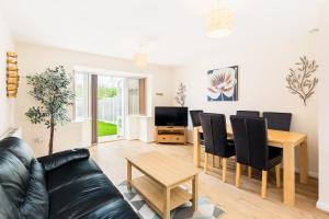 a living room with a black leather couch and a table at Great 4 bed house in Black Country in Tipton