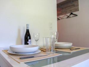 a table with plates and glasses and a bottle of wine at Apartment Grenat 8 by Interhome in Villars-sur-Ollon