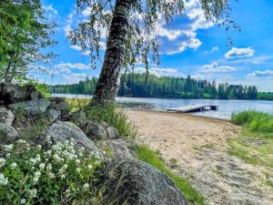 ein Baum am Ufer eines Sees mit einer Anlegestelle in der Unterkunft Holiday Home Lepola by Interhome in Vaskivesi