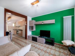 a living room with a green accent wall at Holiday Home La Predaia by Interhome in Barcis