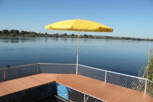 a boat with a yellow umbrella on a river at Kayube Zambezi River House in Livingstone