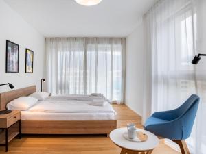 een slaapkamer met een bed en een blauwe stoel bij Apartment LocTowers A4-8-2 by Interhome in Locarno