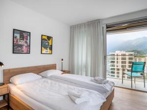 een slaapkamer met een bed en een groot raam bij Apartment LocTowers A4-8-2 by Interhome in Locarno