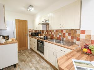 a kitchen with white cabinets and a bowl of fruit on the counter at Sandpiper in Weymouth