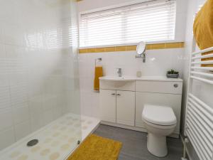 a white bathroom with a toilet and a sink at Sandpiper in Weymouth +33 photos