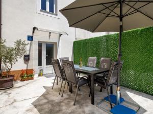 a table and chairs with an umbrella on a patio at Holiday Home Domy by Interhome in Rab