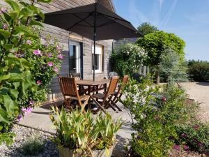 - une table et des chaises sous un parasol dans le jardin dans l'établissement Gîte de la Tuillère, maison contemporaine en bois avec vue et piscine, à Saint-Aulaire