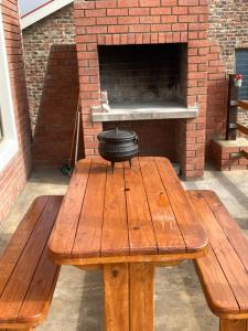 Smitsand Holiday home في ويستاند: طاولة نزهة خشبية أمام فرن من الطوب