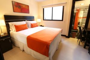een slaapkamer met een groot bed en een oranje deken bij Puerto Mercado Hotel in Montevideo