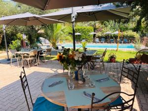 a table with flowers on it under an umbrella at Logis Hôtels La Bastide des Golfs in Mouans-Sartoux