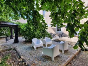 a group of white chairs sitting under a tree at Maison Laurenza/ La Liversoise in Saint-Jean-de-Liversay