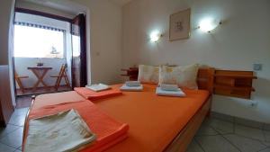 a bedroom with a large bed with orange sheets at Apartments and rooms Bova in Baška