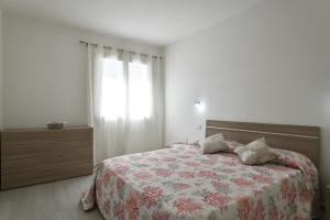 una camera da letto con un letto con copriletto floreale e una finestra di Venere a Cala Gonone
