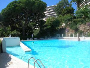 a large blue swimming pool with trees and a building at Splendid sea view 1 Bedroom access to the beach and swimming pool in Vallauris