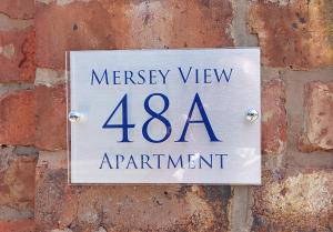 een bord op een bakstenen muur met Mercy View appartement bij Mersey View, Two Bedroom Apartment, Liverpool in Waterloo