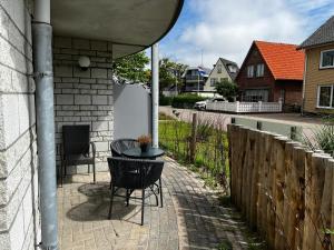 d'une terrasse avec une table, des chaises et une clôture. dans l'établissement Texelheerlijk 10, à De Koog