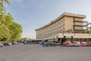 ein großes Gebäude mit auf einem Parkplatz abgestellten Autos in der Unterkunft SHG Hotel Bologna in Zola Predosa