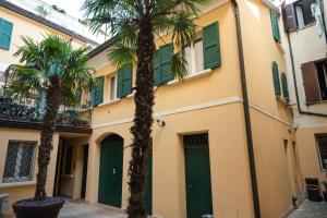 dwie palmy przed budynkiem z zielonymi drzwiami w obiekcie Appartamento La Piazzetta w mieście Carpi