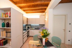 una cucina con armadi bianchi e un tavolo con fiori di Appartamento La Piazzetta a Carpi