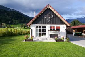 uma pequena casa com um relvado verde em frente em Tischlmühle Appartements & mehr em Gröbming