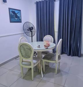 a table and chairs and a fan in a room at Plistbooking 3 Bedroom Duplex, City View Estate in Pakuro